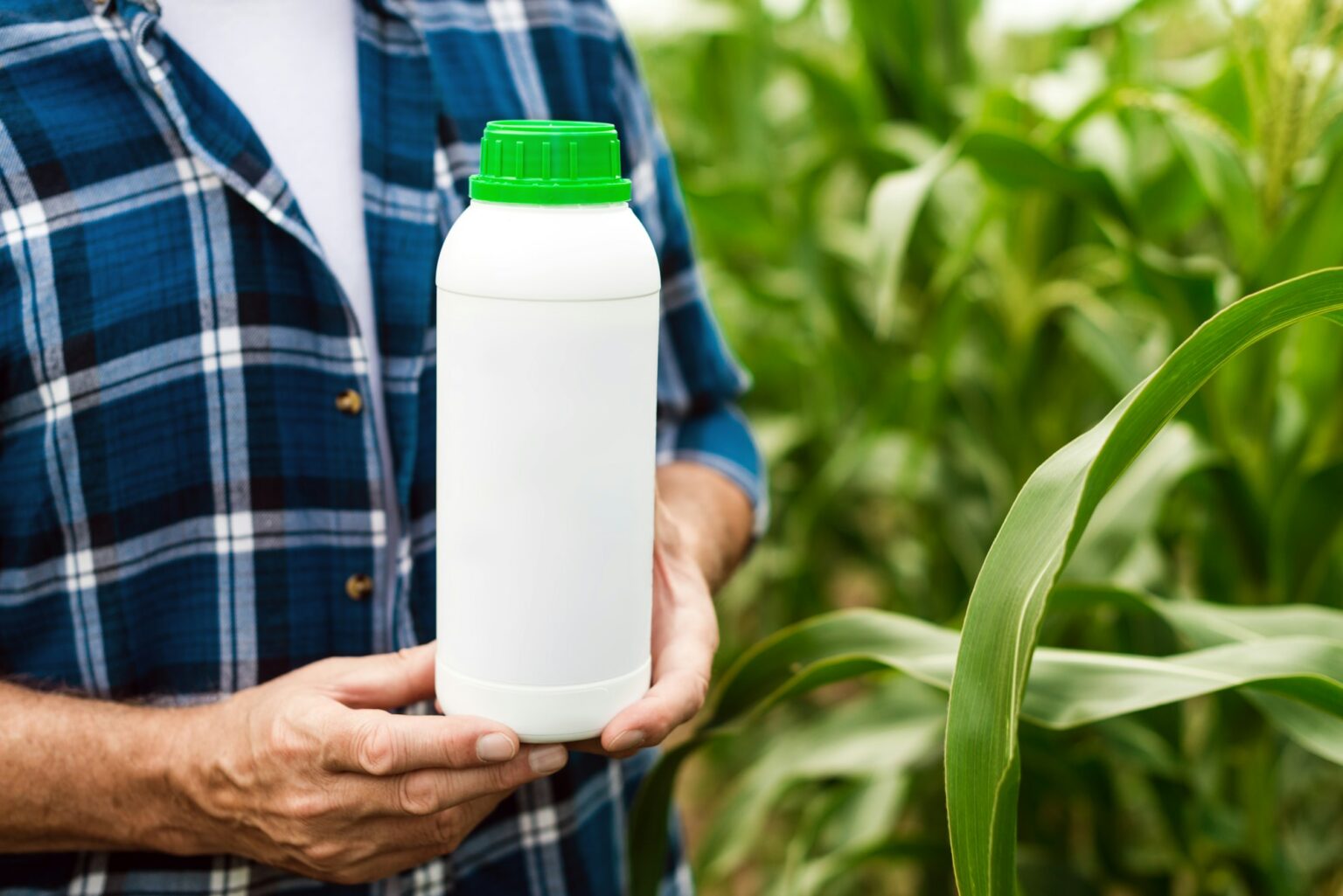 Closeup the bottle with chemical fertilizers in the male hands of farmer